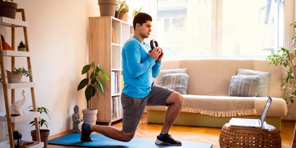 Man doing lunges at home following online workout.