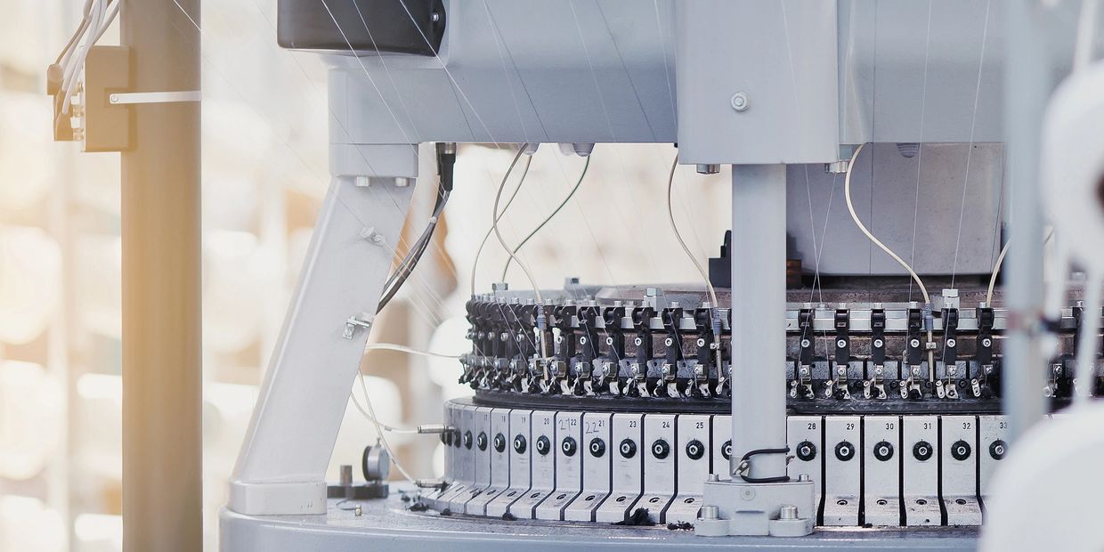 Close-up of an industrial knitting machine with numbered sections and threads.
