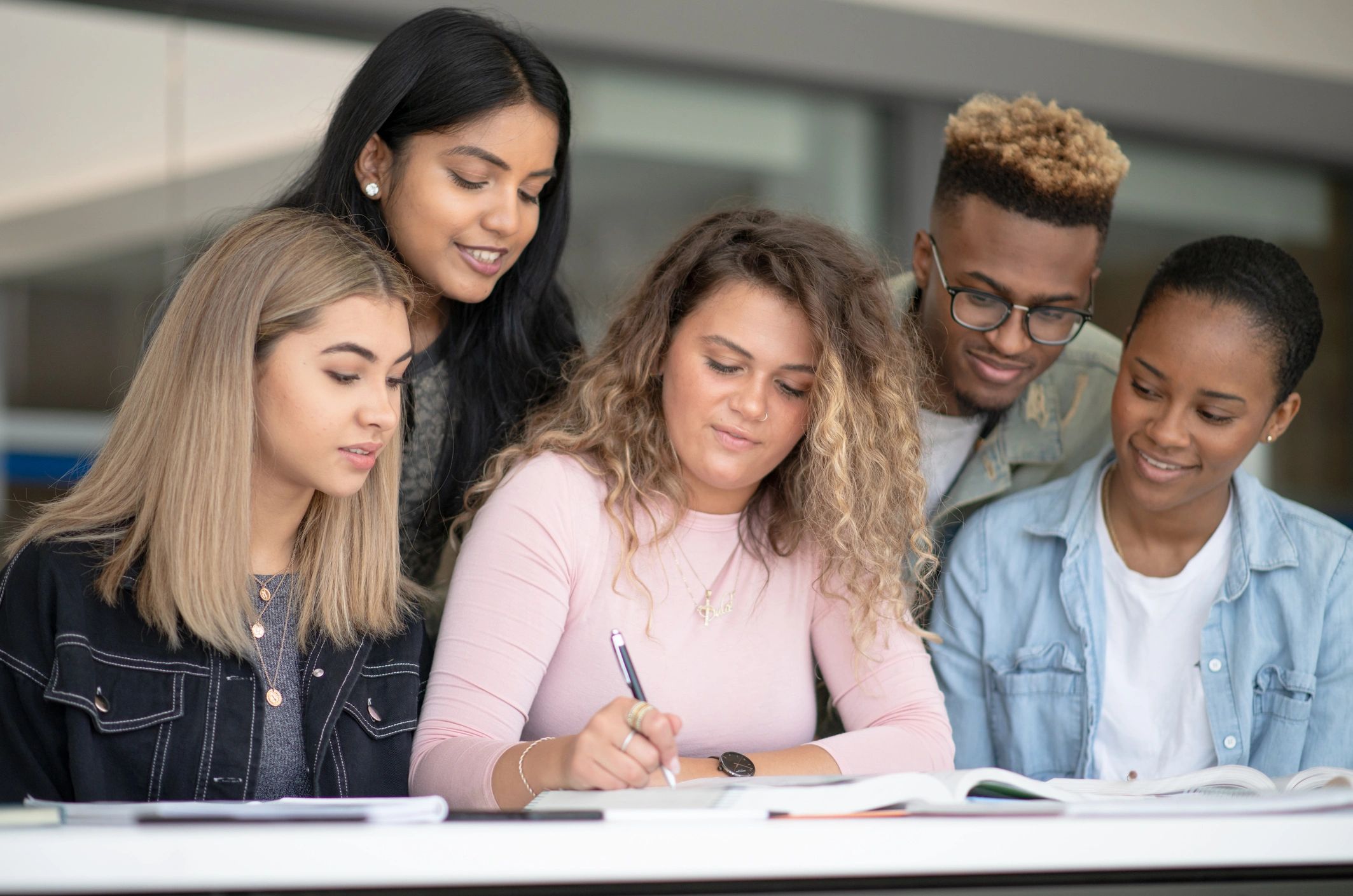 Group of international students studying together at a campus table.