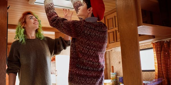 Two people installing a skylight in a cozy wooden room.