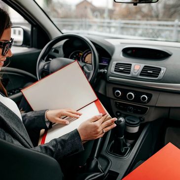 Woman reviewing documents inside a car, smiling and focused.