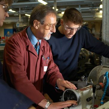 Instructor teaching students how to operate a lathe machine in a workshop.
