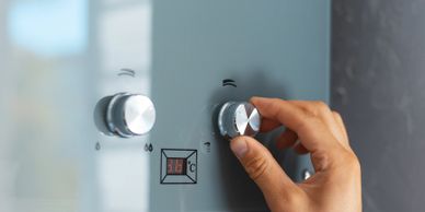 Hand adjusting temperature control on a modern water heater.