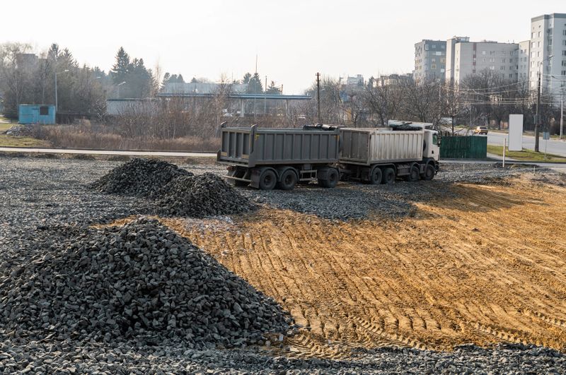 A dump truck is dumping gravel on a construction site. Dump truck dumps its load of gravel on a new road construction project. Road building. Preparing of the fundament for a asphalting