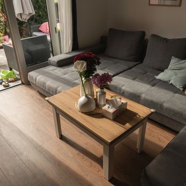 Cozy living room with a gray sofa and a wooden coffee table adorned with flowers and tissue box.
