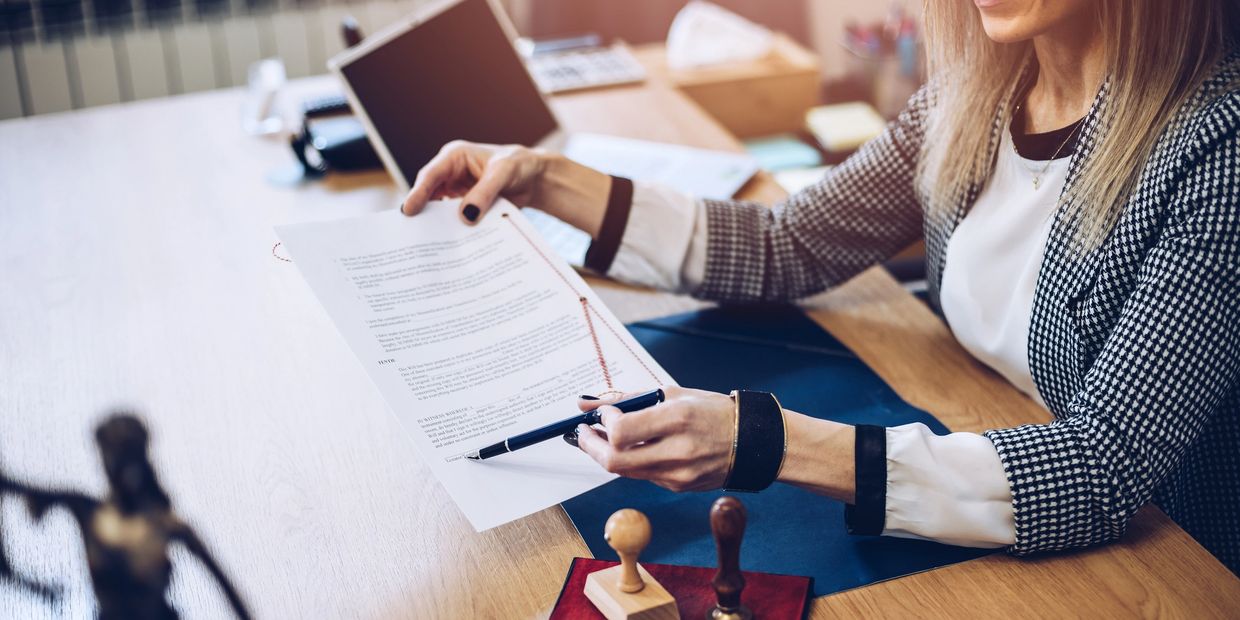 A woman reviewing and pointing at a legal document in an office setting.