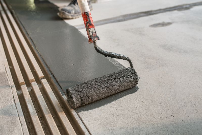 Manual worker installing non slip surface on the floor next to the drain gully