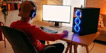 Person gaming on a desktop PC with glowing blue fans.