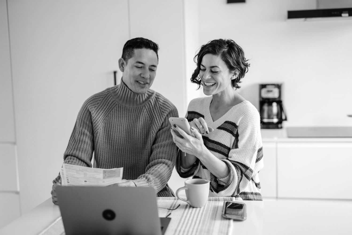 A happy couple managing finances and using a smartphone together.