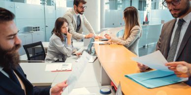 Professionals consulting documents at a reception desk.