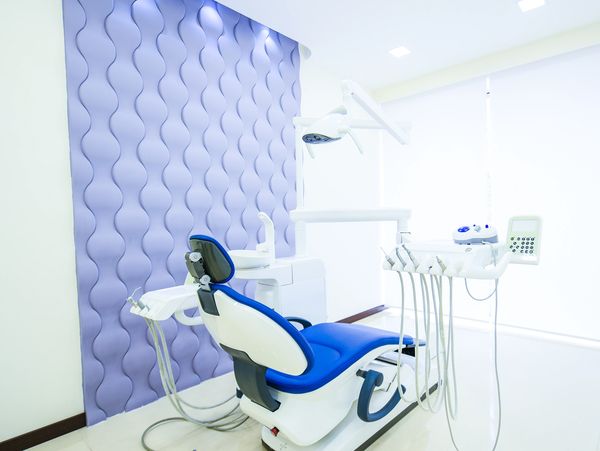 Modern dental clinic room with blue and white dental chair.