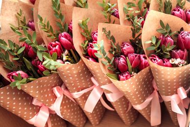 Bouquets of red tulips wrapped in brown paper with pink ribbons.
