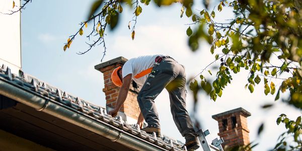 Worker repairing roof under clear sky.