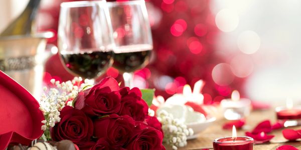 Romantic setting with roses, wine, and candles.