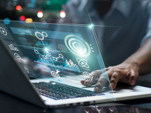 Person interacting with a futuristic transparent digital interface on a laptop.