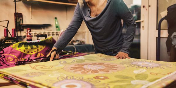 A woman cutting colorful fabric in a sewing workshop.