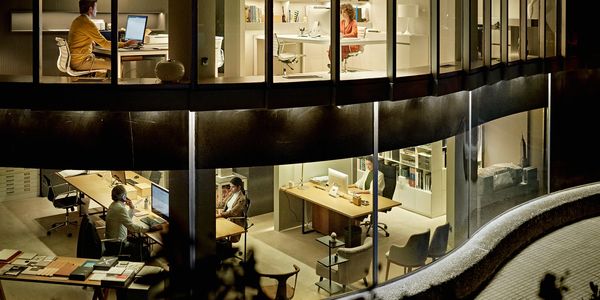 People working late in a modern office building with large glass windows.