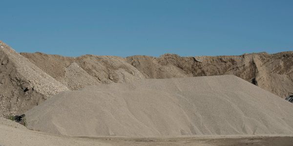 Large piles of gravel under a clear blue sky.