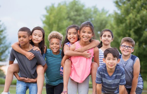 Group of smiling children forming a circle looking down.