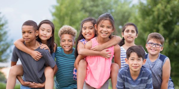 Group of smiling children forming a circle looking down.