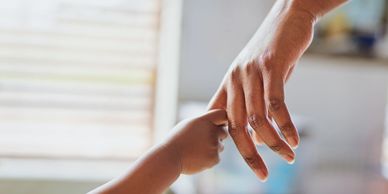 A baby's hand gently holding an adult's finger in a tender moment.