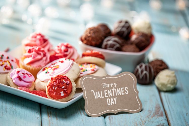 Valentine's Day treats with decorated cookies and chocolates on a blue wooden table.