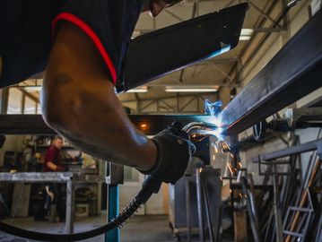 Worker welding metal with sparks flying.