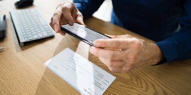 Person photographing a check with a smartphone.
