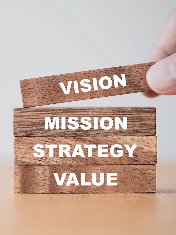 Wooden blocks labeled with vision, mission, strategy, and value stacked on a table.