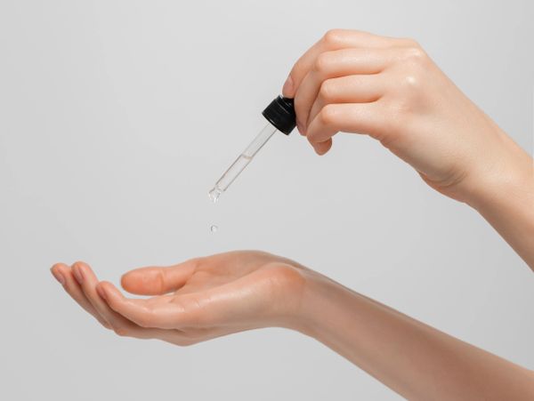 Hand applying liquid from dropper to palm.