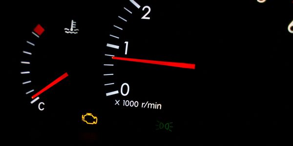 Close-up of car dashboard showing tachometer and check engine light.