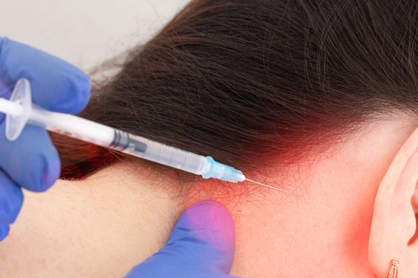 Gloved hands inject a needle into the neck behind the ear, highlighting pain relief.