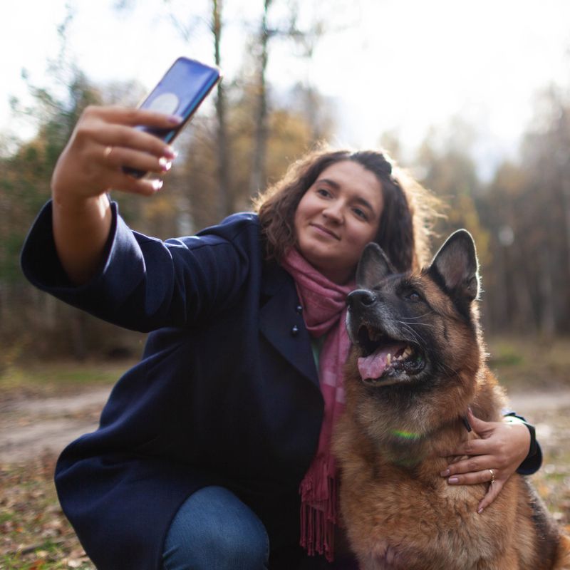 Young woman and german shepherd in the park taking selfie