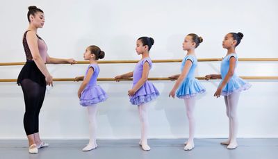 Ballet instructor with young students at barre.
