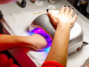Person using a UV nail lamp for gel manicure.