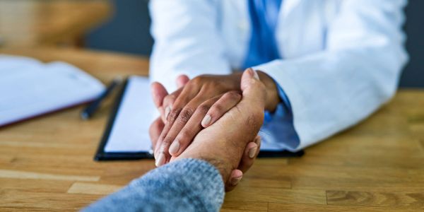 Doctor holding patient's hand for support.