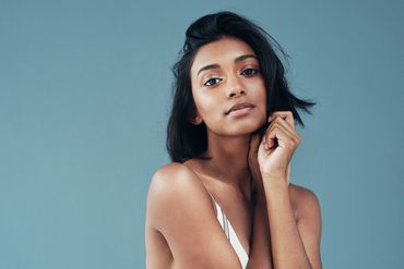 Portrait of a confident woman against a blue background.