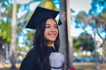 Smiling young woman in graduation cap outdoors.
