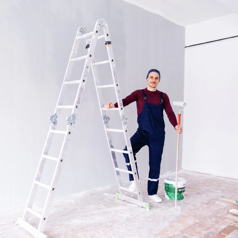 A happy male decorator smiles at the camera while standing next to his tools