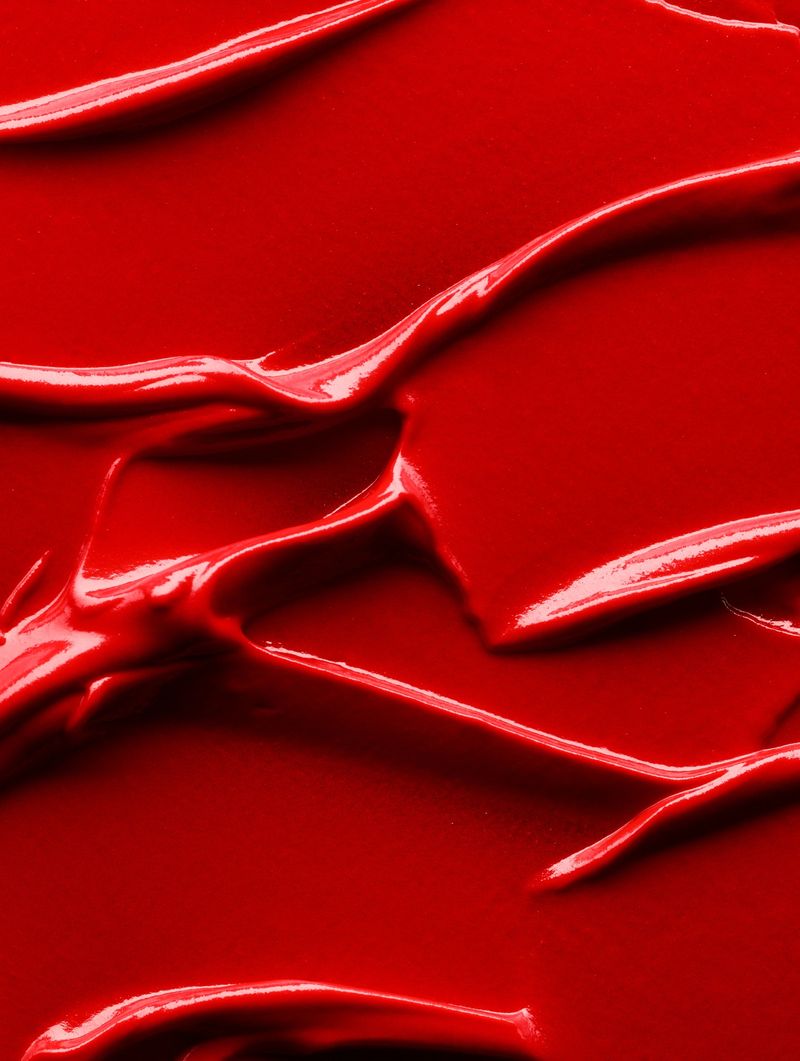 Cosmetic background of red smudged lipstick close up