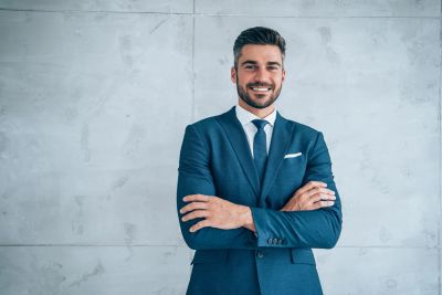 Confident businessman in blue suit standing with arms crossed.