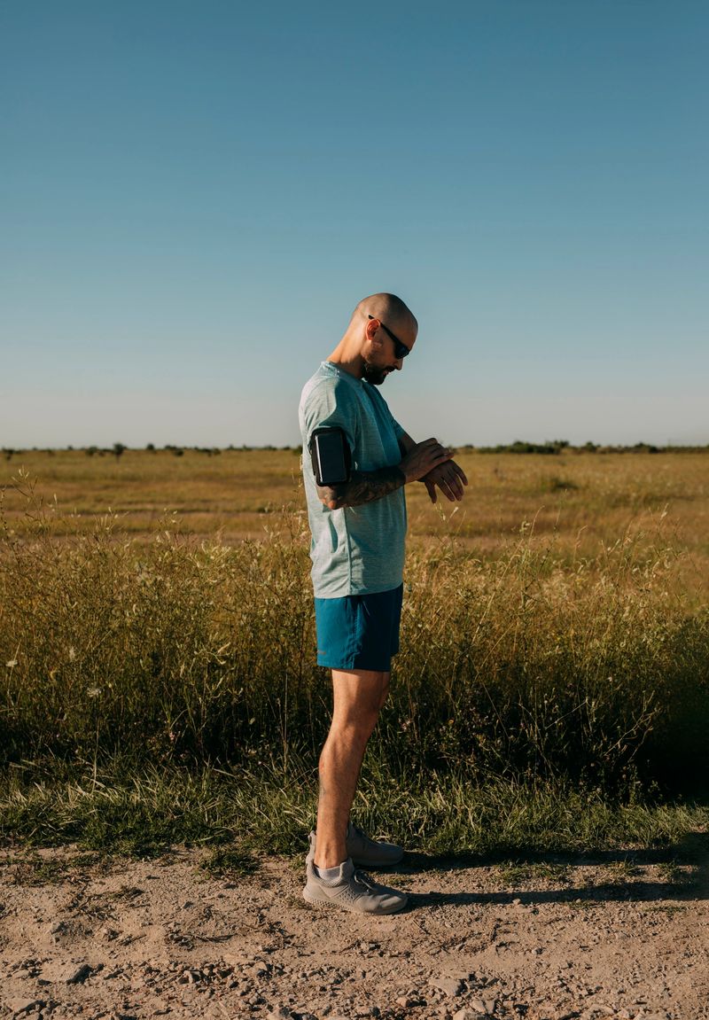 Young bald man in blue sportswear measuring his pulse on a smartwatch