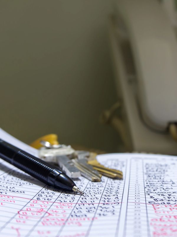 Pen, keys, and a phone on a handwritten ledger or log sheet.