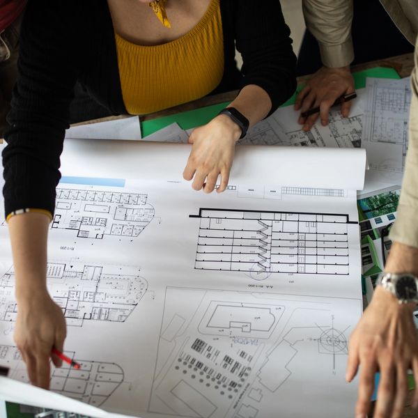 People examining architectural blueprints on a table.