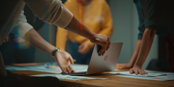 People working collaboratively around a table with a laptop.
