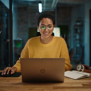Femme souriante utilisant un ordinateur portable au bureau.