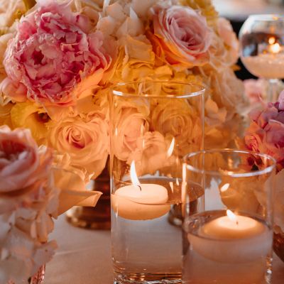 Floating candles in glass vases surrounded by pastel flowers.