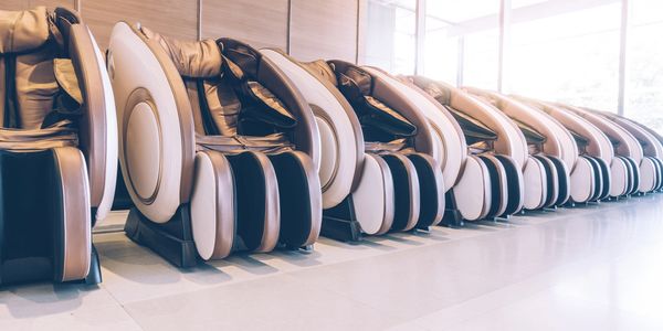 Row of modern massage chairs in a bright room.