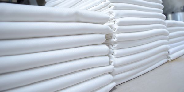 Stacks of neatly folded white fabric on a table.