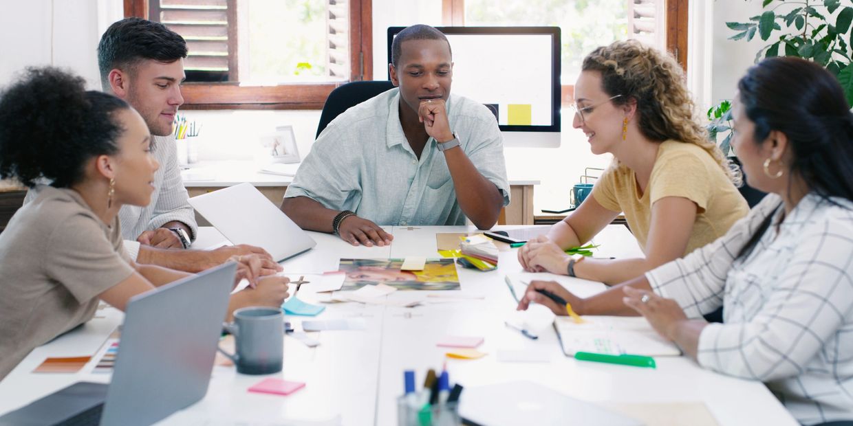 Team discussing ideas around a table in a bright office.